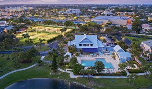 An aerial view of a large property with a swimming pool, tennis courts, and a large building with a blue roof. - Jupiter Dreams at Jupiter Bay! 2 bedroom, 2.5 bath Condo. Close to the beach! (Jupiter)