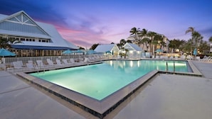 A swimming pool with lounge chairs and umbrellas, surrounded by palm trees and buildings with white roofs. - Jupiter Dreams at Jupiter Bay! 2 bedroom, 2.5 bath Condo. Close to the beach!  (Jupiter)