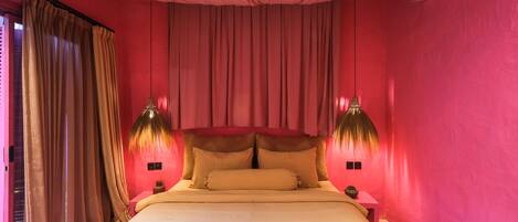 Una habitación con cama, cortinas y dos lámparas fijadas a la pared.