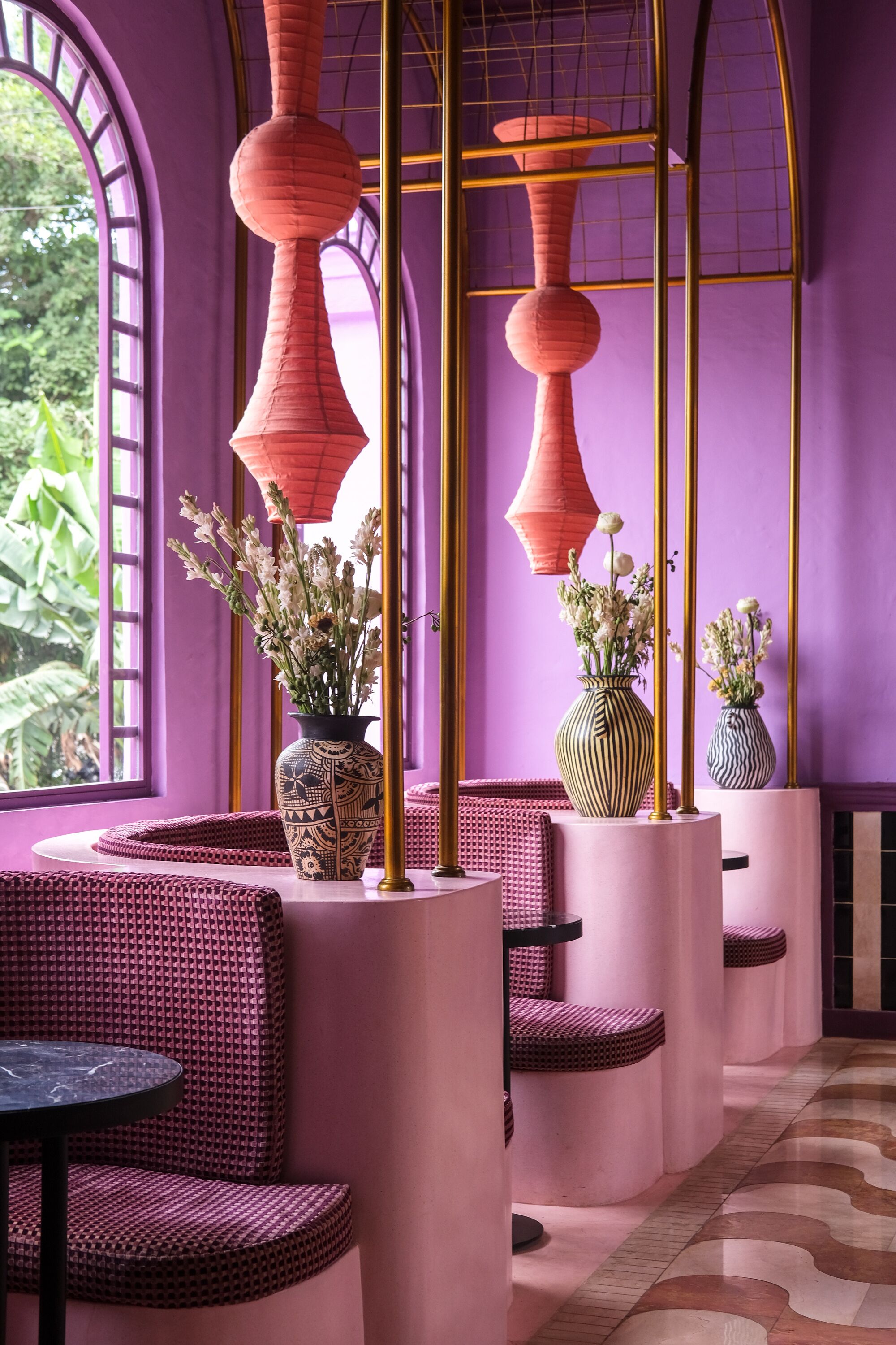 A modern interior with purple walls, round seating, and decorative vases.