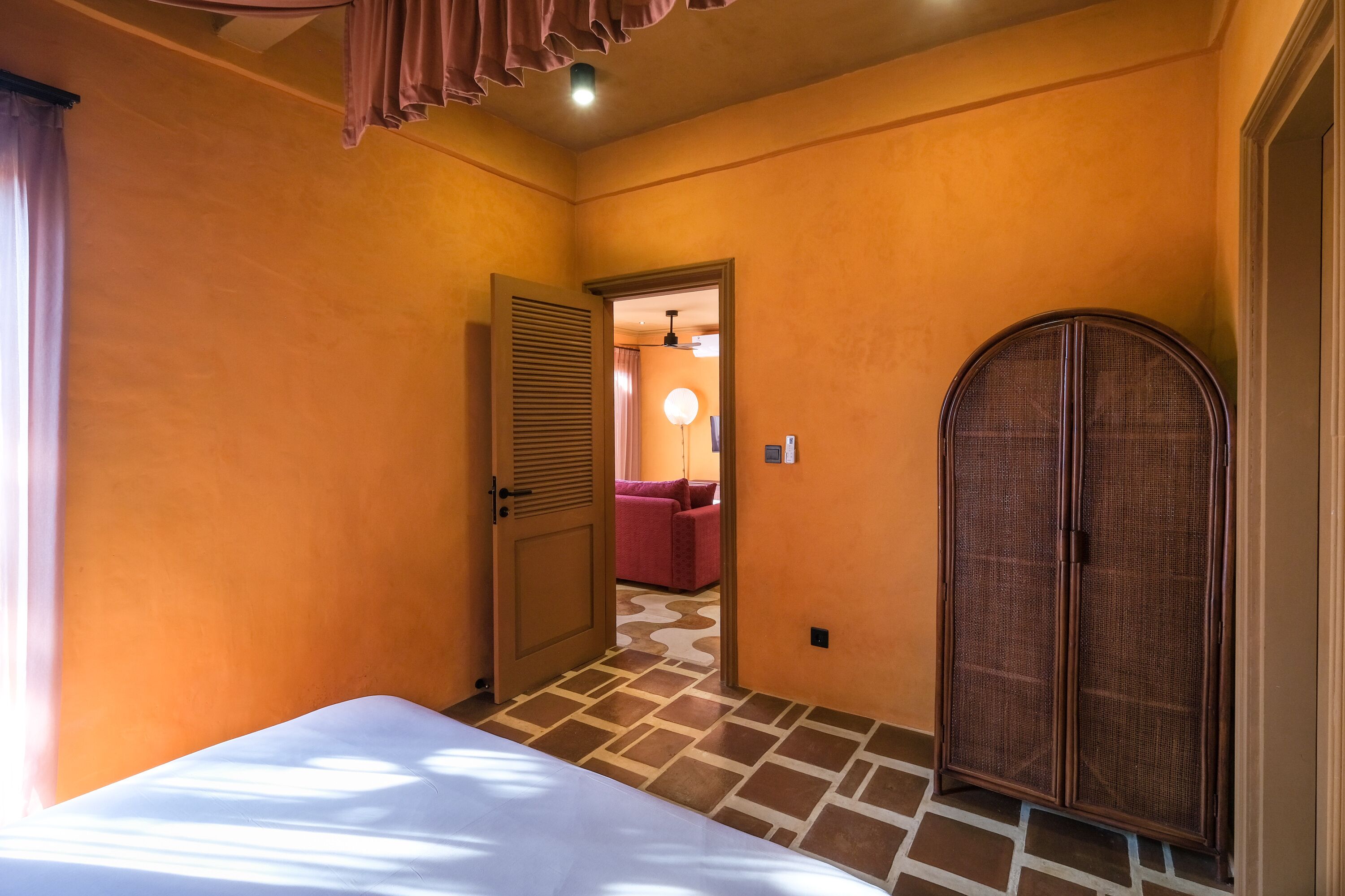 A hotel room with a bed, a wardrobe, and a door leading to another room.