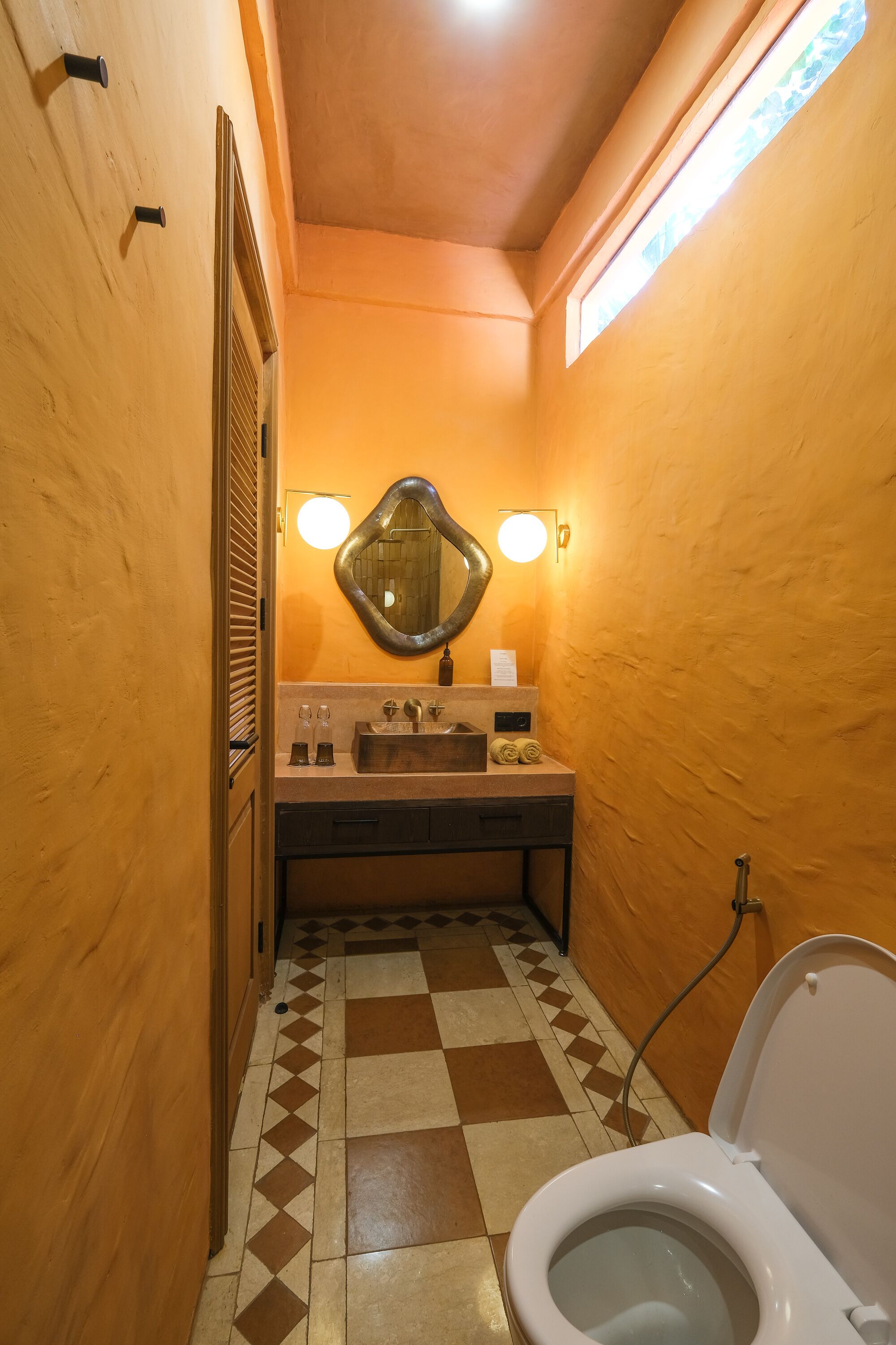 A bathroom with a checkered floor, a sink with a mirror, and a toilet.