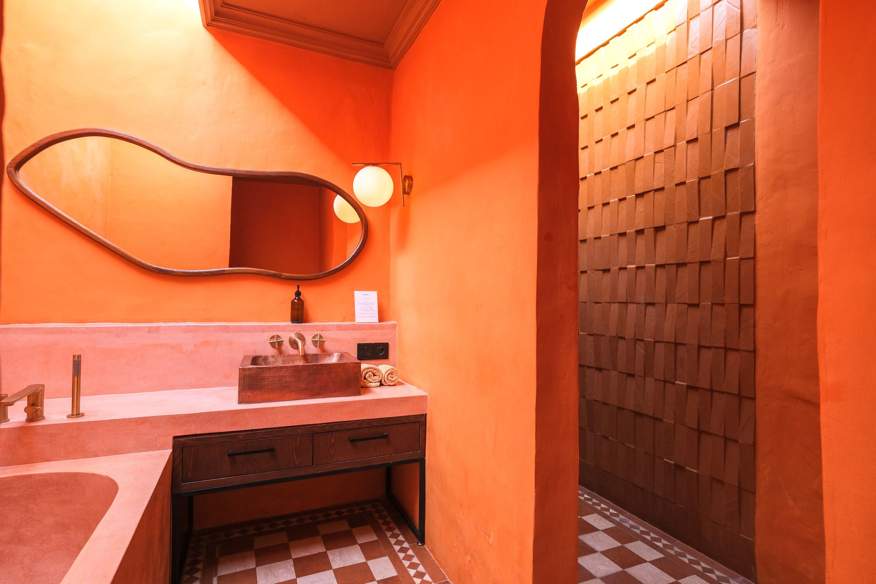 Un baño con un espejo grande, un lavabo con toallero y una zona de ducha con azulejos.