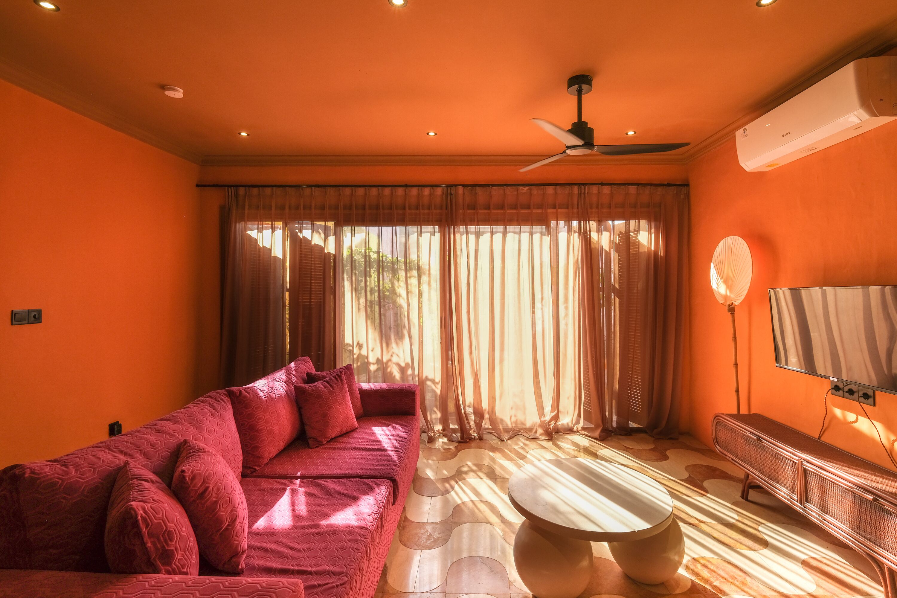 Una habitació amb un sofà vermell, una taula rodona i un ventilador de sostre.