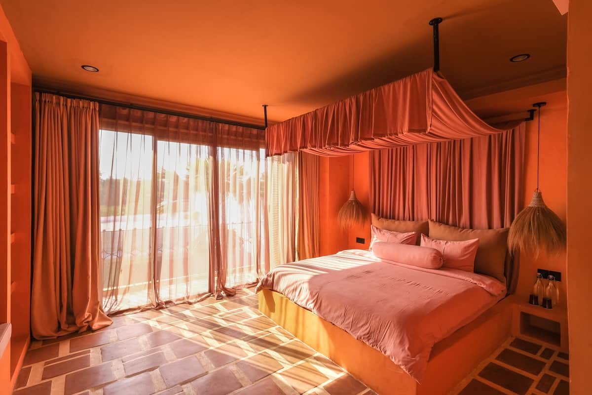 A bedroom with a large bed, curtains, and a view of the outside.