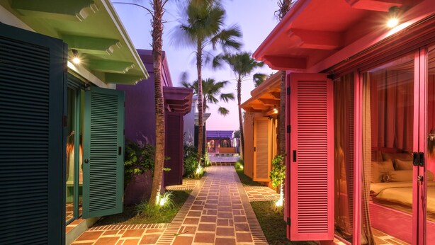A pathway leading to a building with multiple rooms, each with a distinct color theme. - El Barrio Boutique Hotel & Bar (Kerobokan)