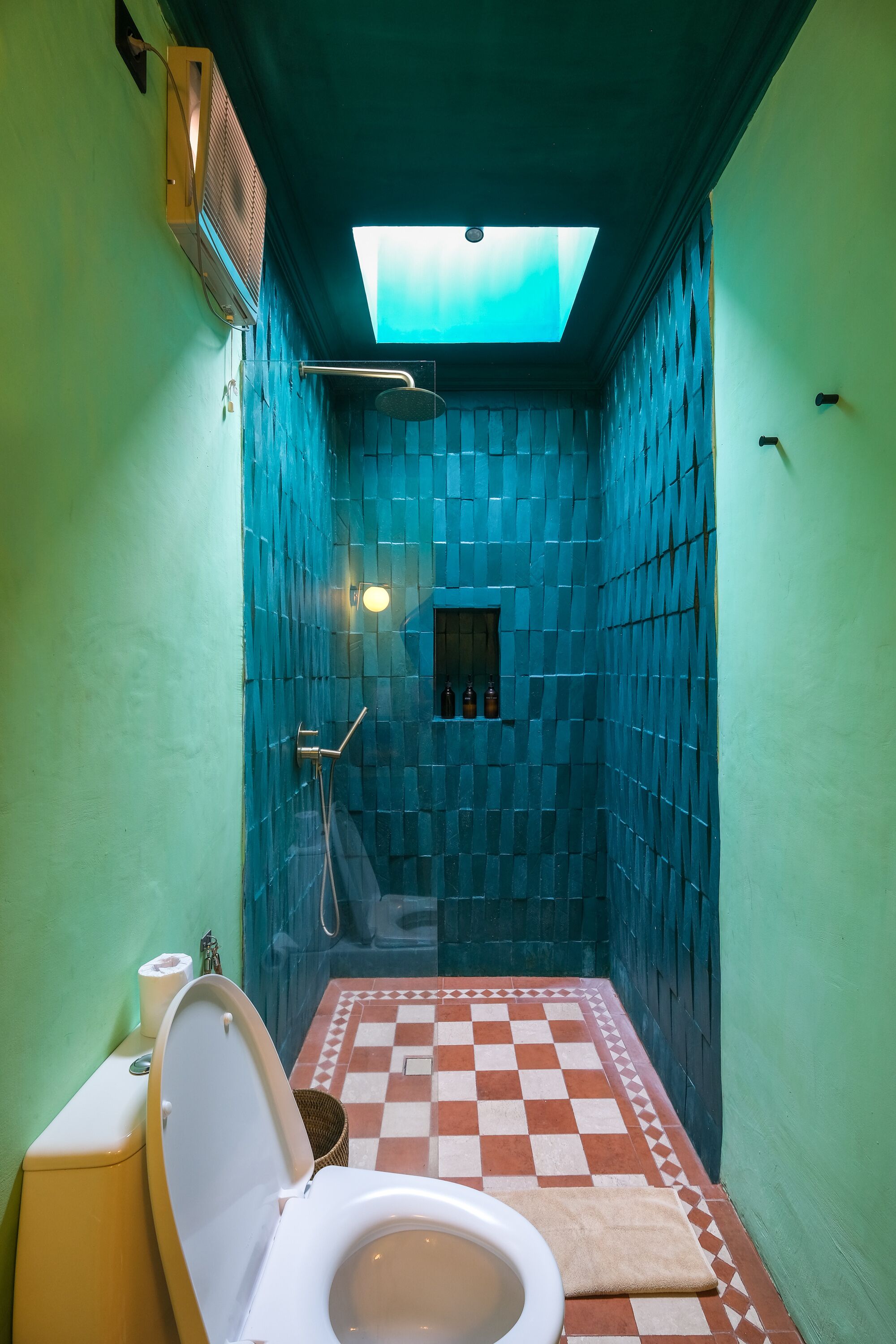 A bathroom with a checkered floor, a skylight, a shower, and a toilet.