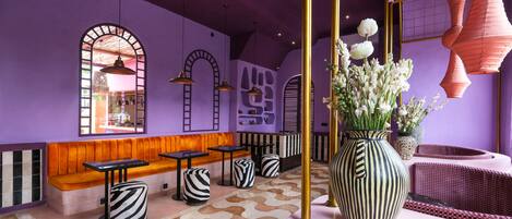 A purple-themed interior with a seating area, tables, and decorative vases.