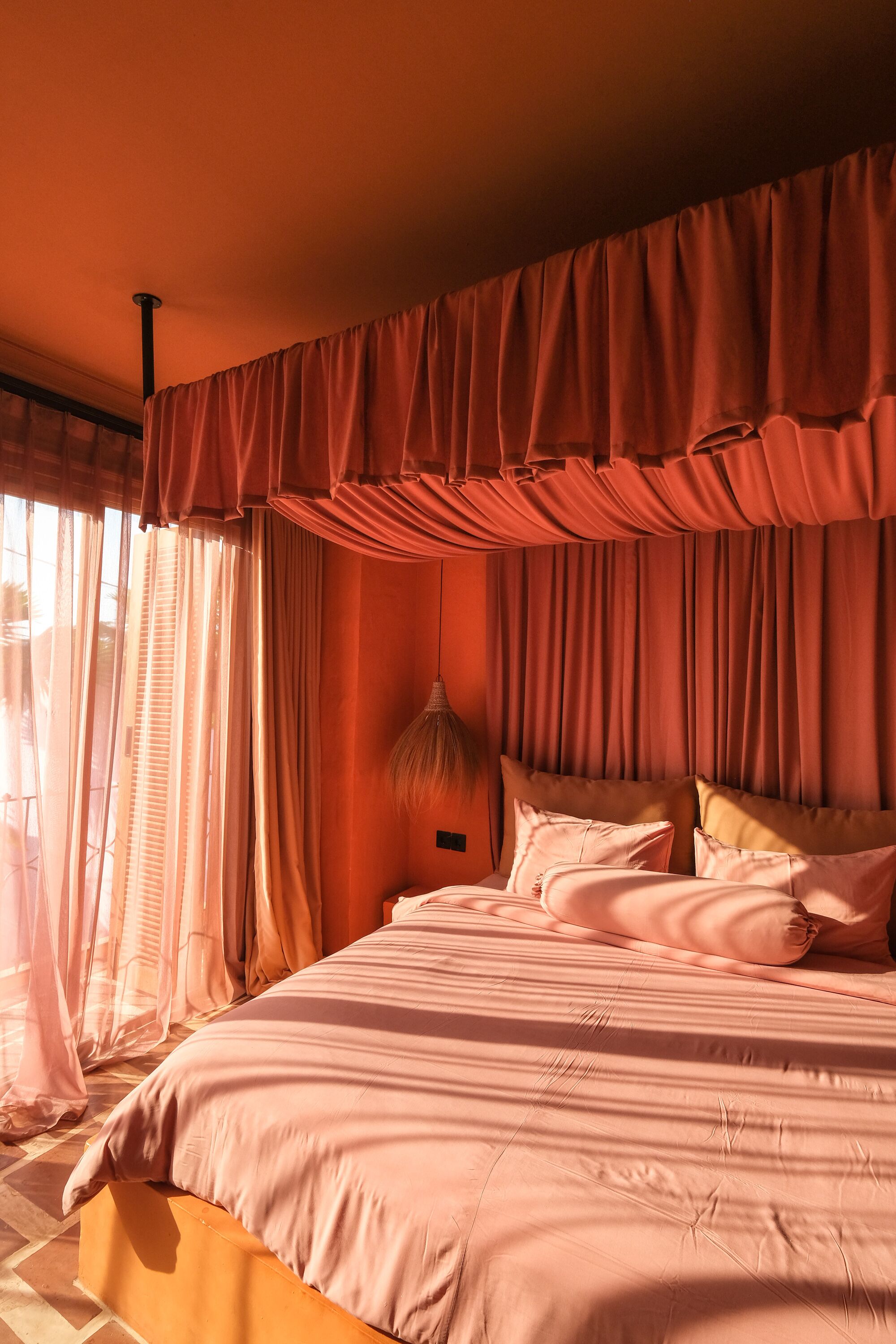 A bedroom with a large bed, curtains, and a nightstand.