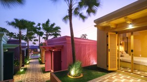 A pathway leading to a building with a red exterior, palm trees, and a well-lit outdoor area. - El Barrio Boutique Hotel & Bar (Kerobokan)