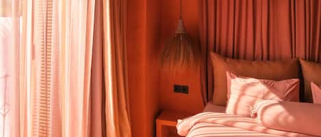 Un dormitorio con cama, cortinas, lámpara y ventana.
