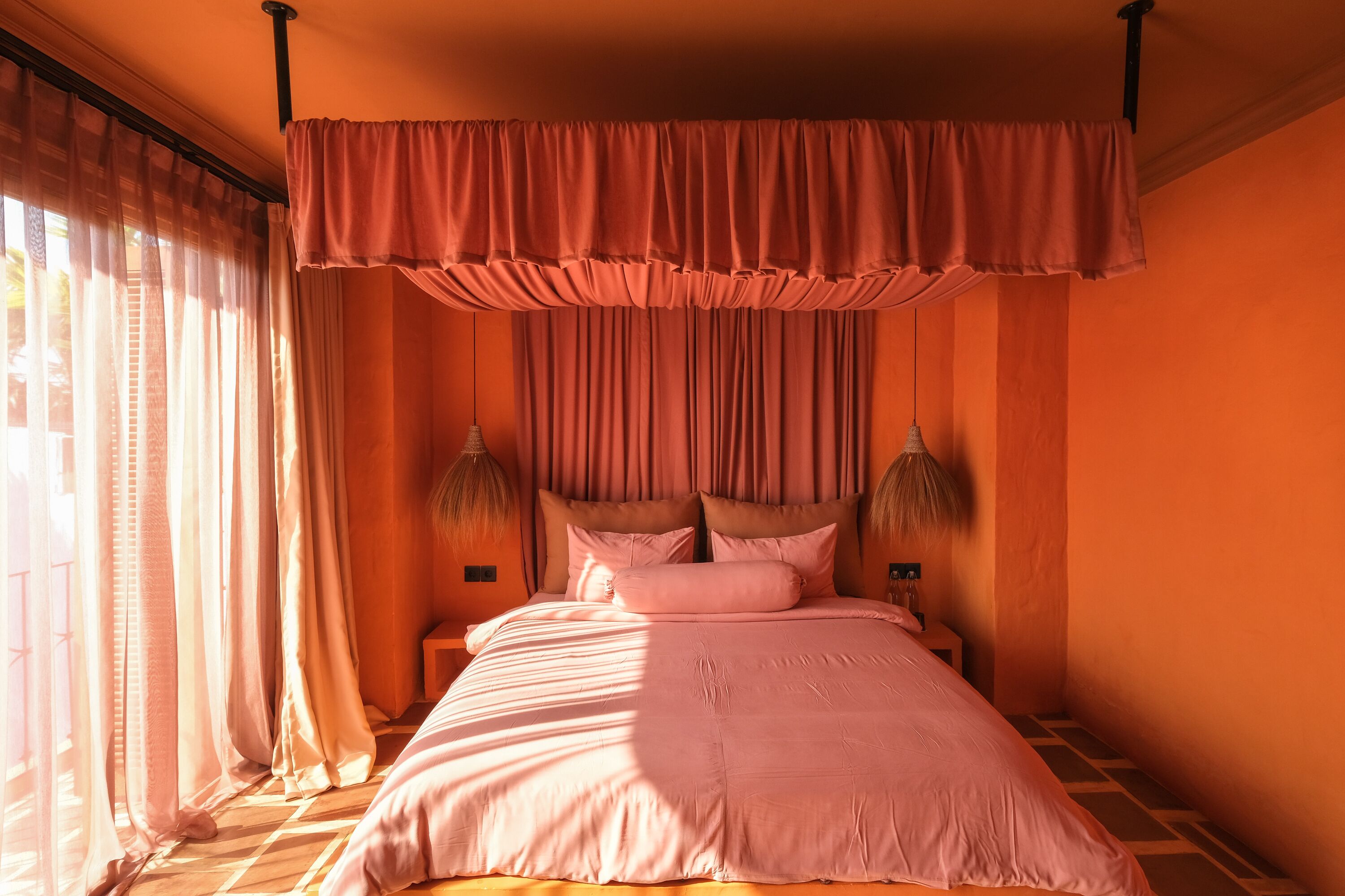 A bedroom with a large bed, curtains, and two wall-mounted lamps.
