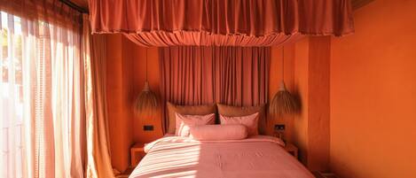 A bedroom with a large bed, curtains, and two wall-mounted lamps.