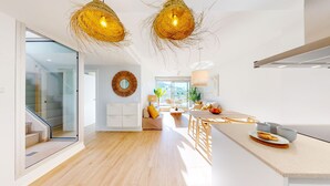 Une cuisine moderne dotée d’un îlot central, un coin repas avec une table et des chaises, et un espace de vie comprenant un canapé et une table basse.