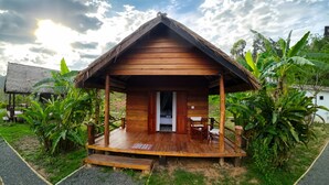 A wooden cabin with a porch, a bed, and a table. - Naga Lodge (Luang Prabang)