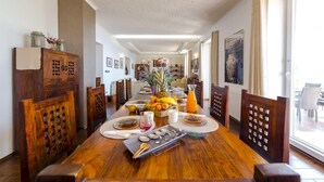 A dining area with a wooden table set for four, surrounded by chairs. There is a buffet table with fruits and beverages in the center. - Private Seaside Villa Sleeps 10 with Infinity Pool (Mlini)