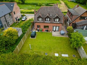 A two-story house with a sloped roof, a fenced backyard, and a parked car. - House -  Sleeps 6 & Free parking (Great Yarmouth)