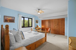 A bedroom with a wooden bed, a ceiling fan, a window with curtains, a wooden wardrobe, and a desk with a chair. - House -  Sleeps 6 & Free parking (Great Yarmouth)
