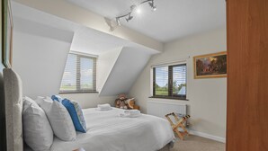 A bedroom with a large bed, a window with blinds, a radiator, a painting on the wall, and a ceiling light fixture. - House -  Sleeps 6 & Free Parking, Pets (Great Yarmouth)