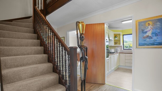 A staircase with a wooden railing, a trophy on a pedestal, and a kitchen area with cabinets and a window. - House -  Sleeps 6 & Free Parking, Pets (Great Yarmouth)