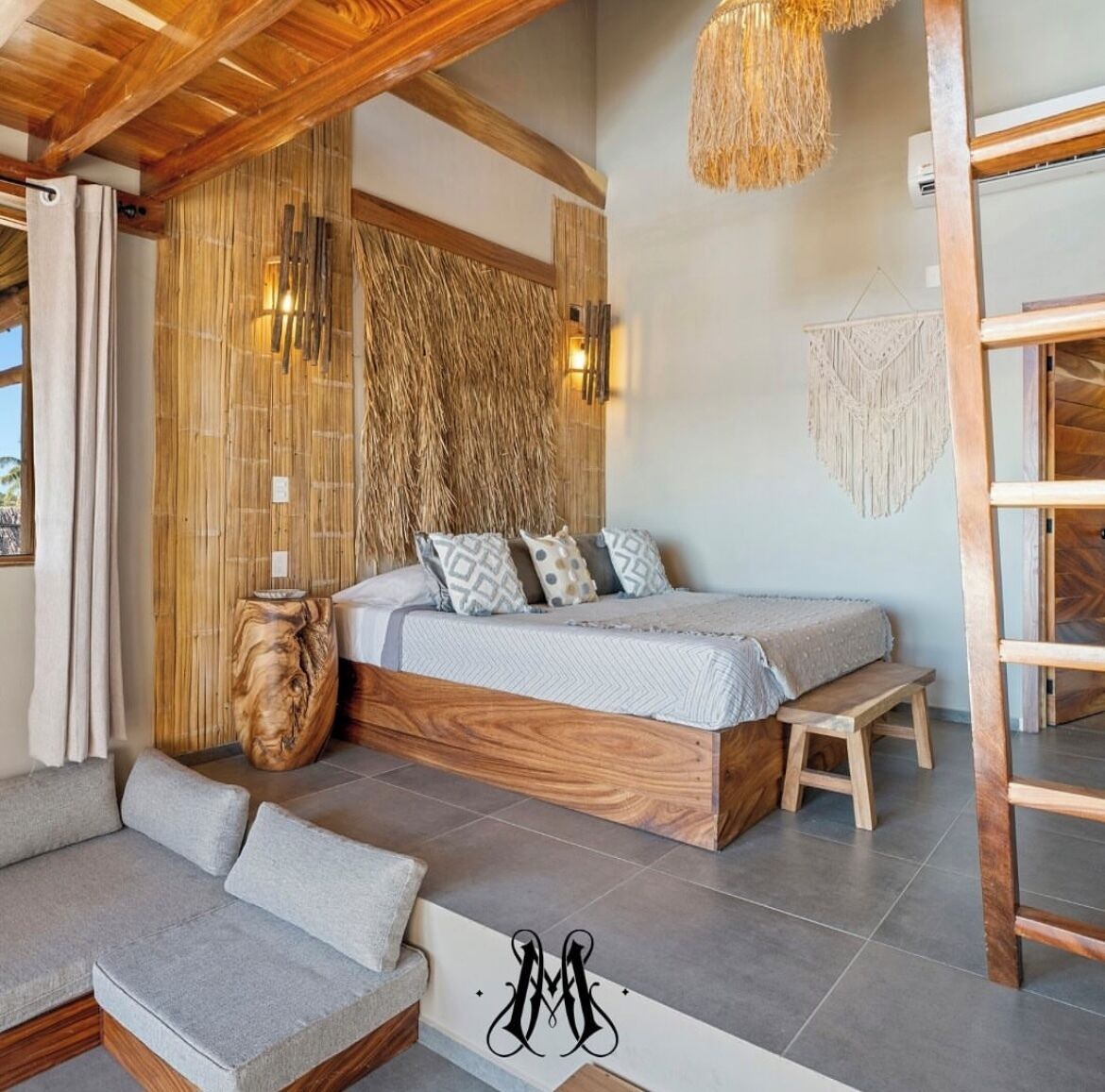 A modern bedroom with a wooden bed, a bench, a woven wall, and a macrame wall hanging.