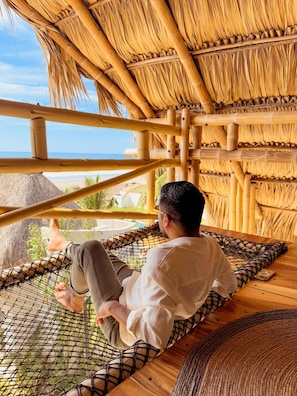 A person reclining on a hammock with a view of the beach and palm trees. - Mare Mio Hotel Boutique (Tonalá)