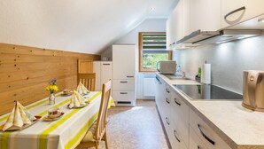 Una cocina con comedor, paneles de madera, un ventanal y electrodomésticos modernos.
