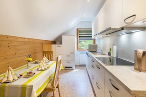 A kitchen with a dining area, wooden paneling, a window, and modern appliances.