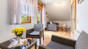 Una habitación acogedora con un sofá de mimbre, una mesita con un florero y vistas a un balcón.