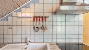 Une cuisine équipée d’un évier, d’une cuisinière et d’ustensiles de cuisine suspendus.