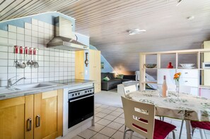 Une cuisine moderne équipée d’un four encastré, d’un évier et d’une cuisinière. On y trouve également un coin repas avec une table et des chaises.