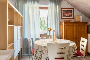 Un coin repas avec une table dressée pour deux personnes, un buffet en bois et un tableau accroché au mur.