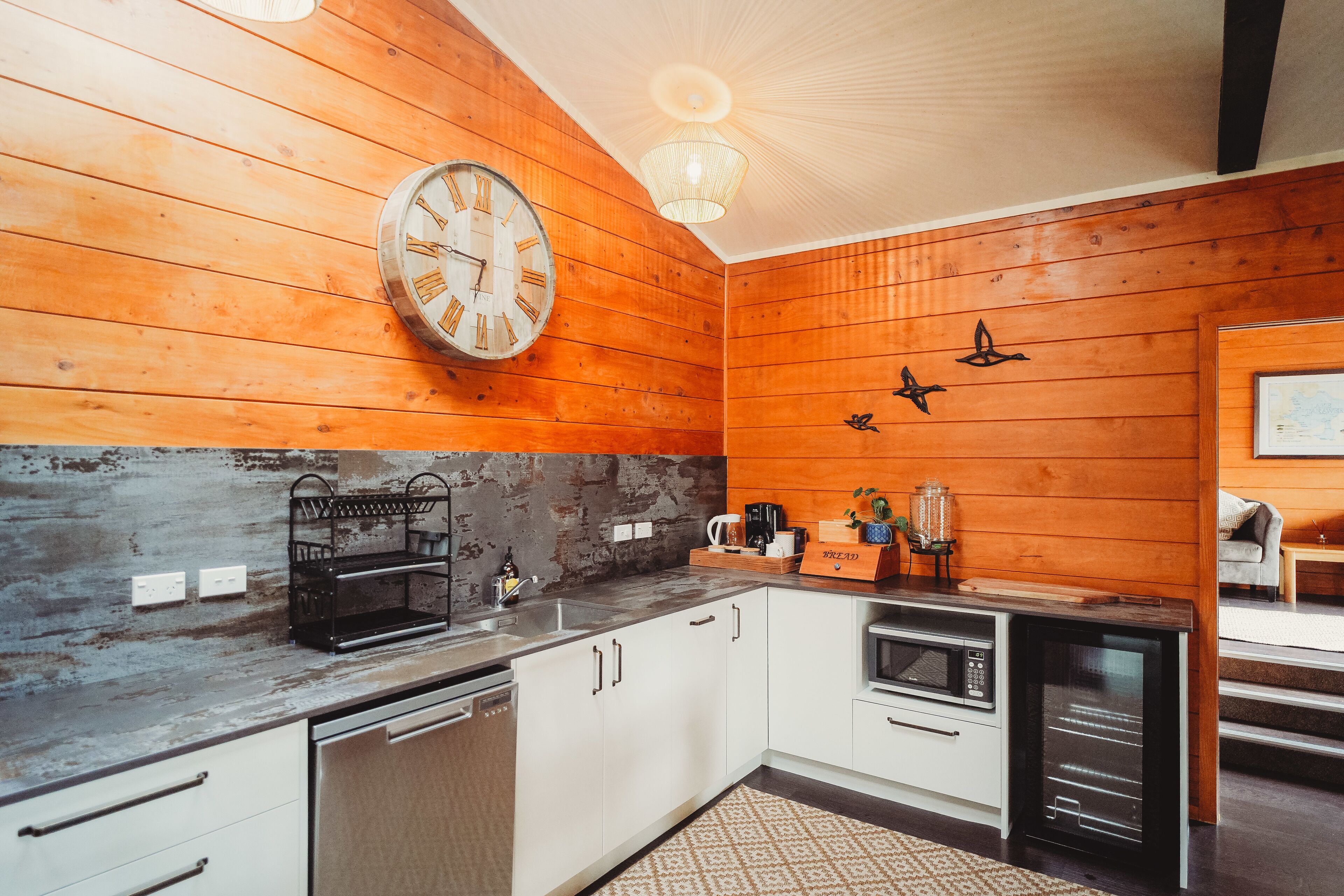 Una cocina con paredes de madera, un reloj y electrodomésticos modernos.