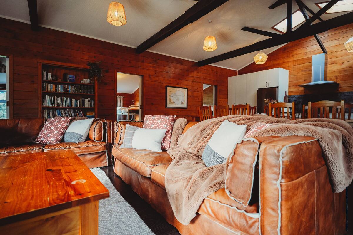 Ein gemütliches Blockhaus-Interieur mit Ledersofa, Holztisch und Bücherregal.
