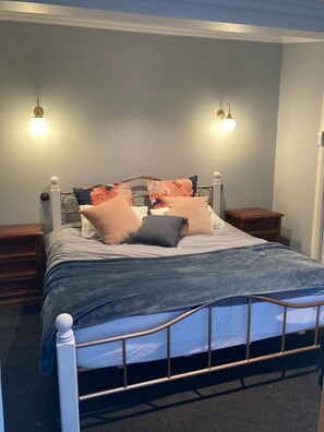 Ein Schlafzimmer mit einem Bett, zwei Nachttischen und Wandleuchten.