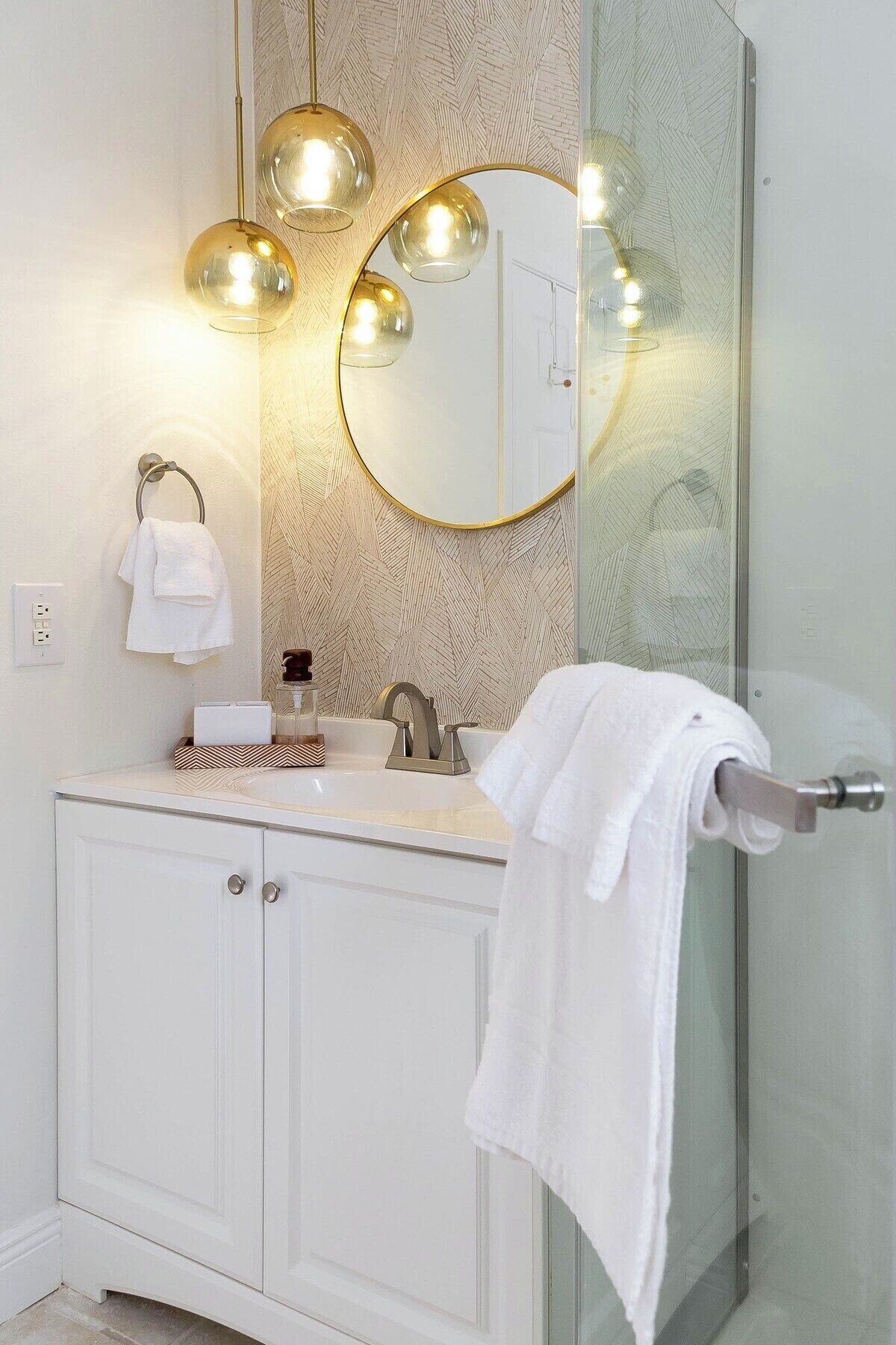 Un baño moderno con tocador, espejo y cabina de ducha de vidrio.