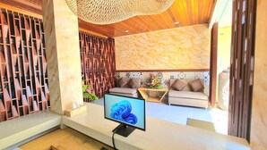 A modern reception desk with a computer monitor, keyboard, and a decorative hanging light fixture. - Kamandaka Living (Kuta)