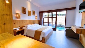 A hotel room with a large bed, a desk, a chair, a phone, and a view of a pool. - Kamandaka Living (Kuta)