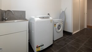 Een wasserette met een wasmachine, droger en een wasbak.