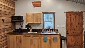 Eine kleine Küche mit Holzausstattung, einer Mikrowelle, einem Spülbecken und einem Fenster.