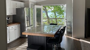 Une cuisine moderne dotée d’un grand îlot central, de meubles blancs et offrant une vue sur l’extérieur.