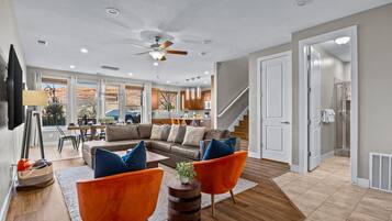 Un salon moderne comprenant un canapé, deux fauteuils, une table basse et un ventilateur de plafond.