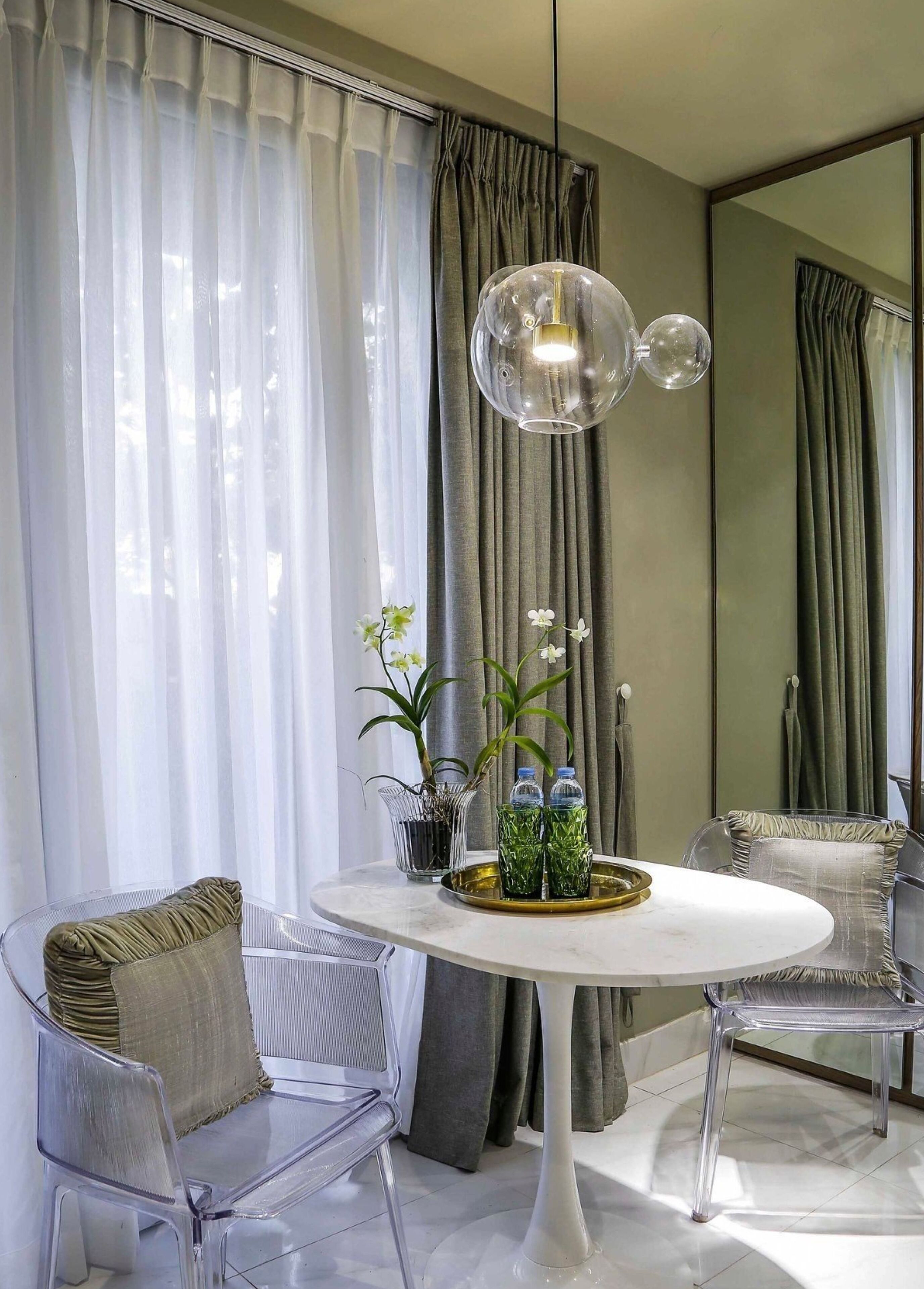 Un espace repas moderne avec une table ronde, des chaises transparentes et un luminaire suspendu.