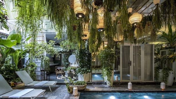 A serene indoor pool area with lounge chairs, hanging plants, and ambient lighting. - Bed In Town Saigon (Ho Chi Minh City)