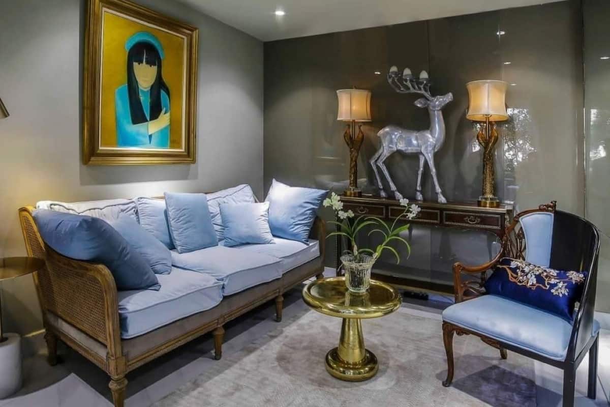 Uma sala de estar moderna com um sofá, poltronas, uma mesa de centro e objetos decorativos, incluindo uma pintura e uma escultura de veado.