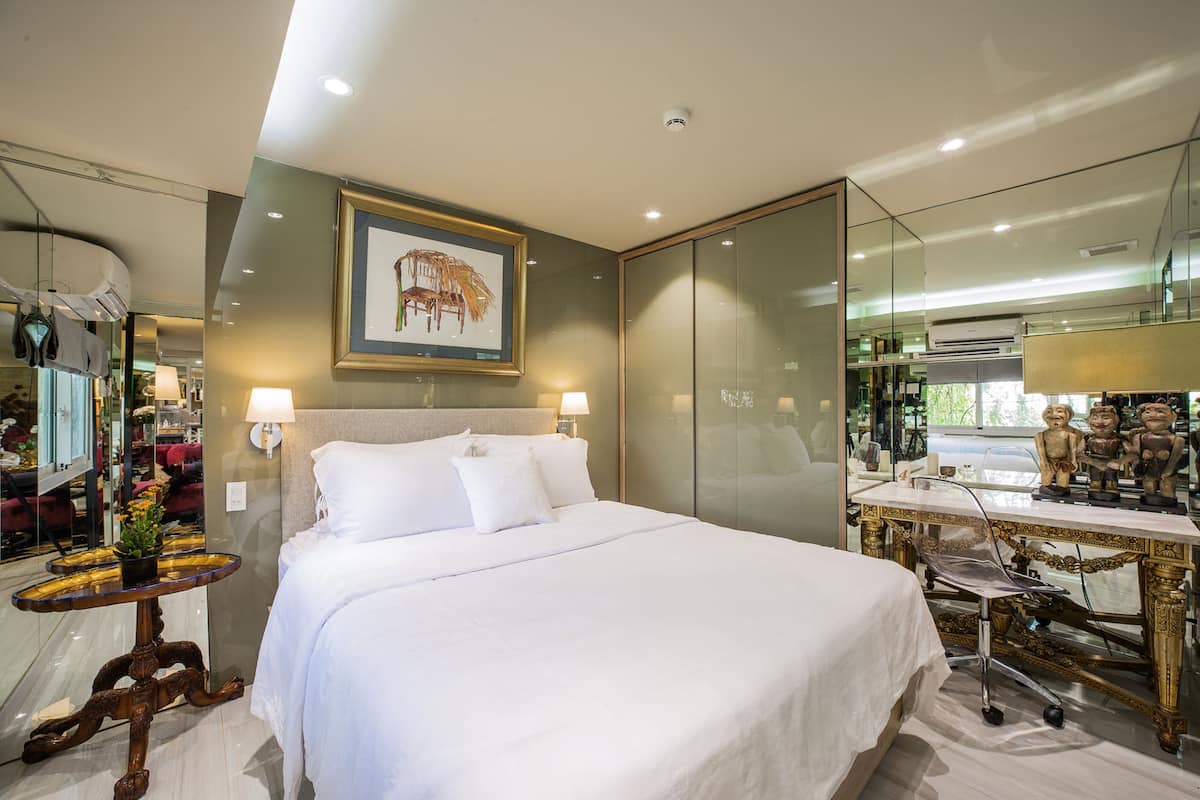 Quarto de hotel moderno com uma cama grande, uma escrivaninha com cadeira, um espelho e um quadro na parede.