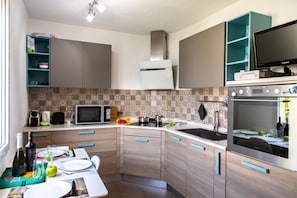 Cozinha moderna com micro-ondas, fogão e uma TV Samsung em um suporte.
