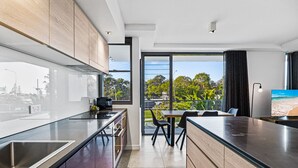 Una cocina moderna con una isla grande, un área de comedor con vistas y un televisor a la derecha.