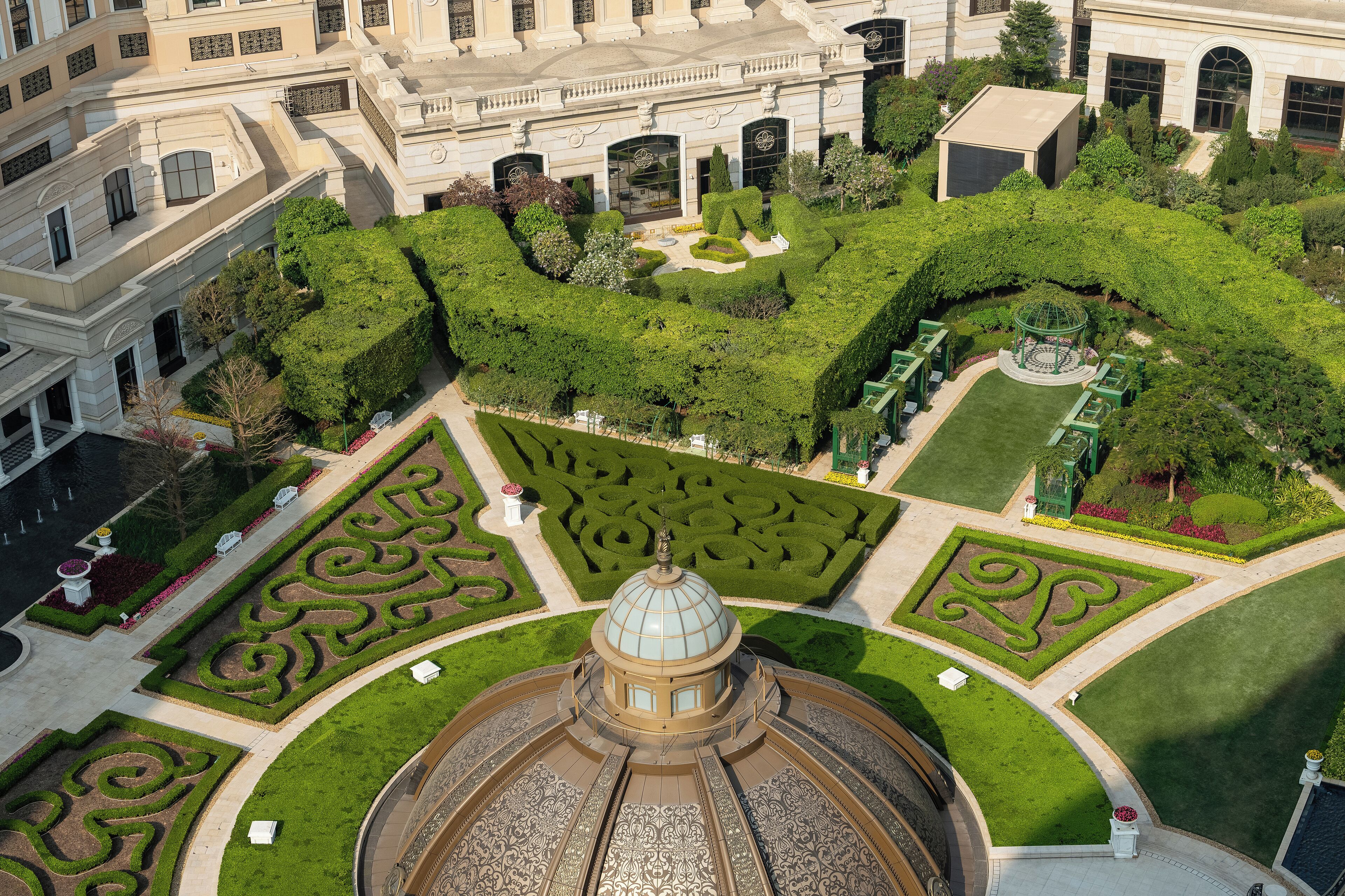 Un gran edificio histórico con una cúpula central y jardines formales que lo rodean.