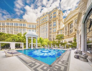 A luxurious hotel pool area with a central fountain, sun loungers, and a gazebo. - The Karl Lagerfeld (Cotai)